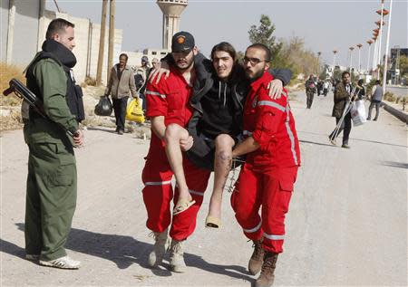 Volunteers from the Syrian Arab Red Crescent carry a sick man as Syrian families leave the besieged town of al-Moadamiyeh, which is controlled by opposition fighters, in Damascus countryside October 29, 2013. REUTERS/Khaled al-Hariri