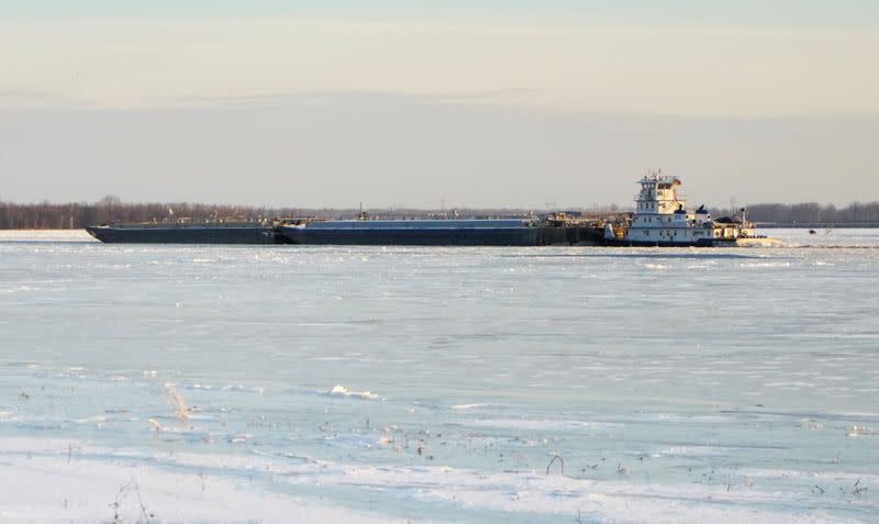 A barge plows through a frozen Mississippi River during cold weather in Alton