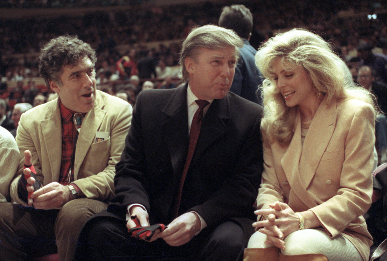 FILE - Actor Elliott Gould, left, joins Donald Trump, center, and Marla Maples at courtside during an NBA basketball game between the Phoenix Suns and the New York Knicks at Madison Square Garden, in New York, Tuesday, March 6, 1991. (AP Photo/Steve Freeman, File)
