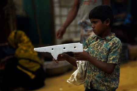 A Rohingya refugee boy holds styrofoam fashioned into the shape of a gun at Kutupalong refugee camp in Cox's Bazaar, Bangladesh, March 27, 2018. REUTERS/Clodagh Kilcoyne