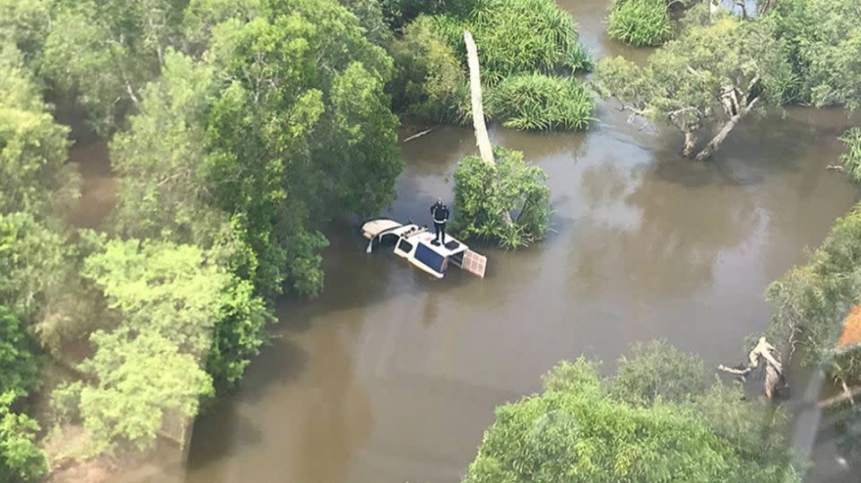 The police officer stood on the roof waiting to be rescued as water surrounded his vehicle. Source: Northern Territory Police, Fire and Emergency Services