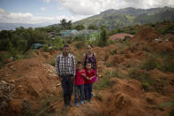 Eleuterio Esquivel, 51, left, poses with his wife, Elsa Mejia, 40, and their twins, Ibis Esquivel, left, and Noel Esquivel, 7, at the site of their home destroyed by a landslide triggered by hurricanes Eta and Iota in the village of La Reina, Honduras, Wednesday, June 23, 2021. Home to about 1,000 people, the town in western Honduras was hit by two powerful hurricanes within three weeks, natural disasters made far worse by local deforestation and climate change. La Reina was buried by a landslide. (AP Photo/Rodrigo Abd)