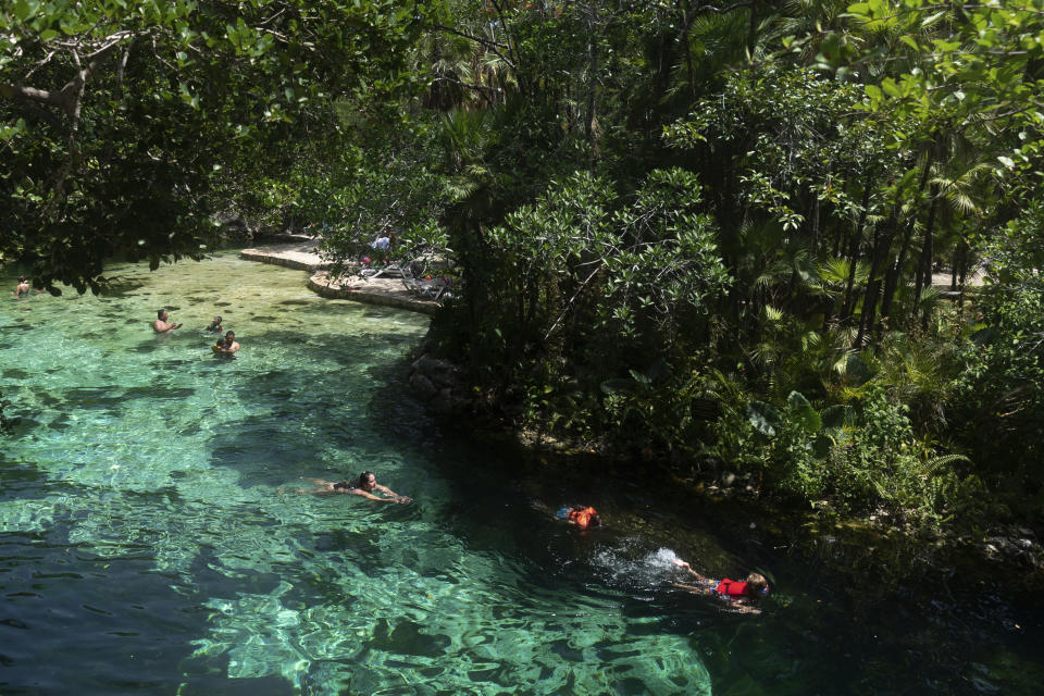 Turistas se bañan en un cenote de Playa del Carmen (México), donde debería funcionar una de las paradas del Tren Maya, en foto del 3 de agosto del 2022. El presidente Andrés Manuel López Obrador dice que los detractores del proyecto son "pseudoambientalistas", en tanto que algunos lugareños expresan temor de que el tren contamine las cuevas que los abastecen de agua. (AP Photo/Eduardo Verdugo)