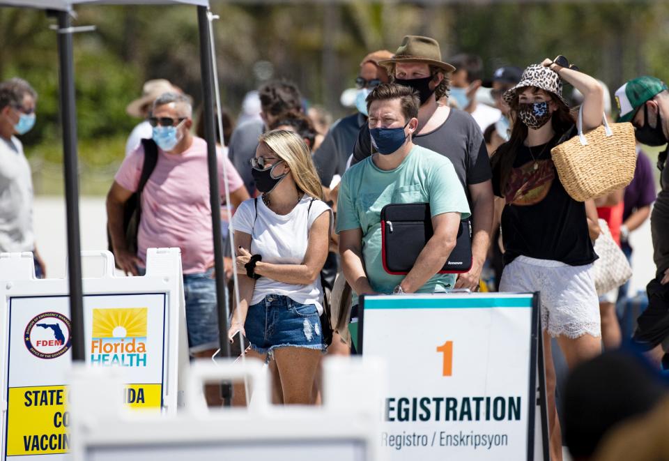 People wait in line Sunday to receive a COVID-19 vaccine at a one-time pop-up vaccination site in Miami Beach.