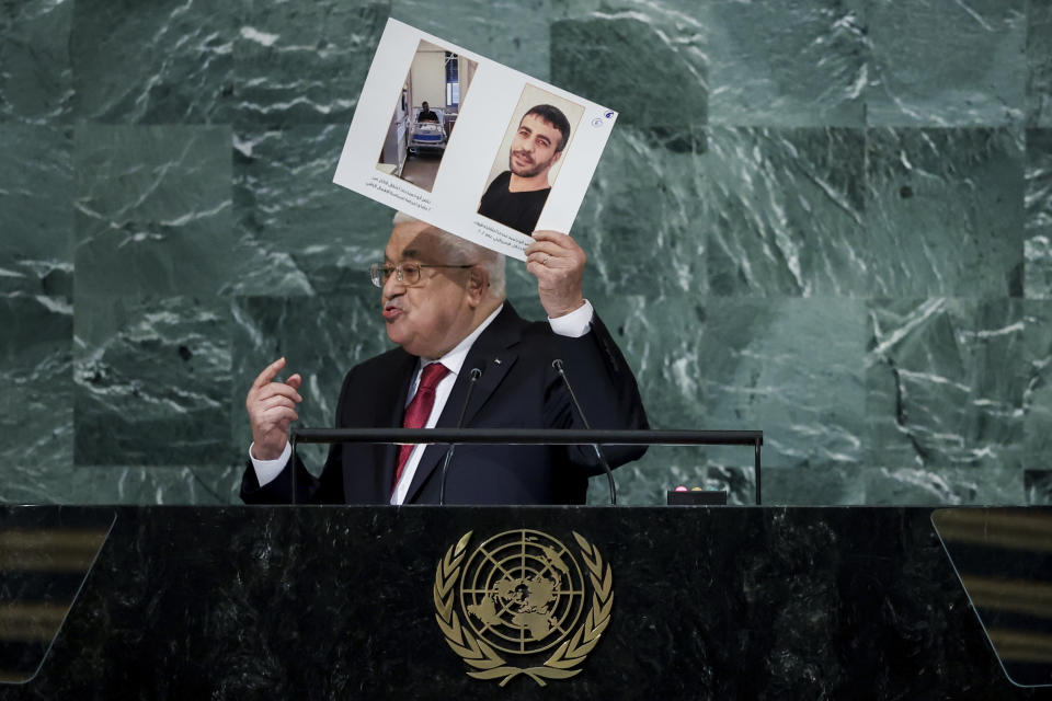 Palestinian President Mahmoud Abbas holds up photographs while addressing the 77th session of the United Nations General Assembly, Friday, Sept. 23, 2022, at the U.N. headquarters. (AP Photo/Julia Nikhinson)