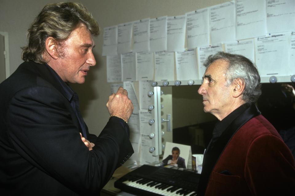 Son succès, Johnny Hallyday le doit en partie à Charles Aznavour, qui a été l'un des premiers à lui faire confiance. C'est également ce dernier à qui Johnny doit d'avoir rencontré sa "Lady Lucille". Après avoir été la cible d'une tentative de meurtre, le rockeur s'est installé chez son ami et mentor pendant plusieurs mois. Et lors d'un dîner avec Roger Vadim, qui cherche quelqu'un pour donner la réplique à Catherine Deneuve dans son prochain film, Les Parisiennes, le réalisateur a un coup de coeur pour le jeune chanteur. (Photo by PAT/Gamma-Rapho via Getty Images)