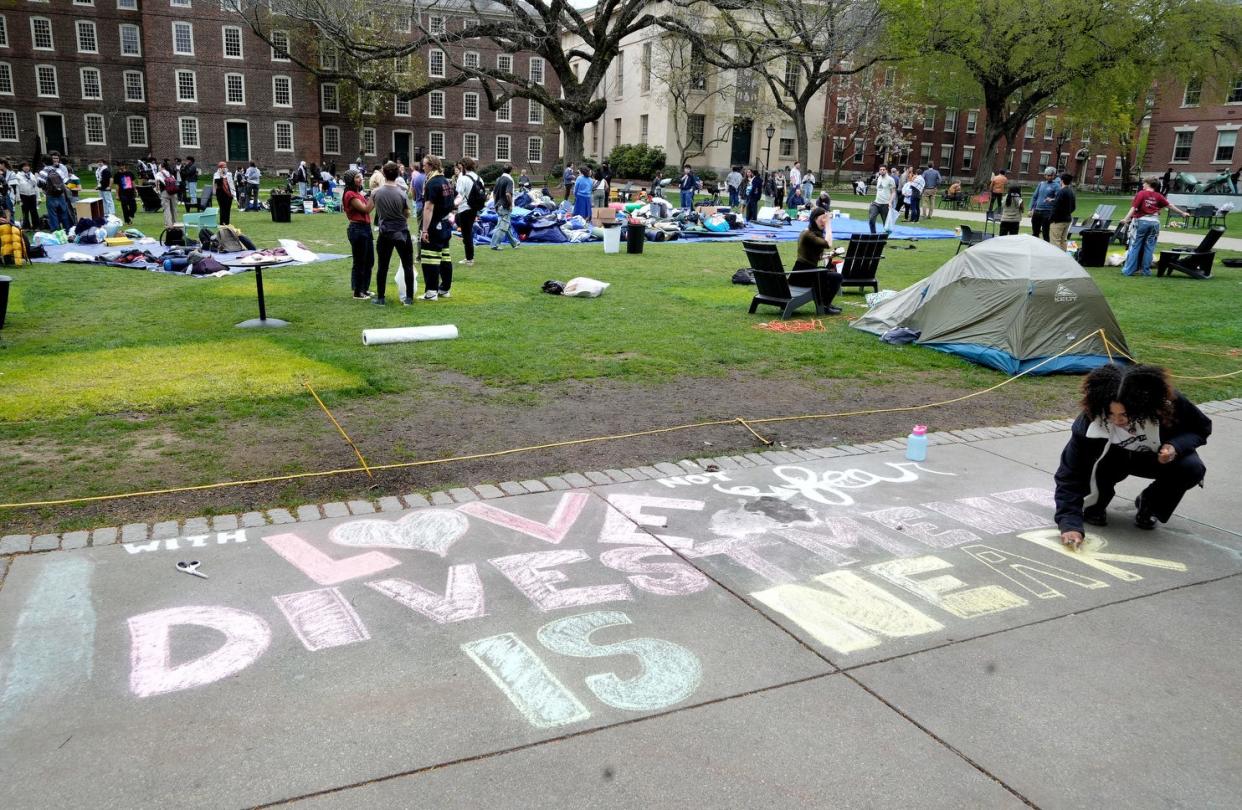 Brown freshman Rayna Franklin puts a final touch to chalk lettering next to the Main Green as protesters at Brown University pack up the Gaza Solidarity encampment Tuesday afternoon well ahead of the five oÕclock deadline on April 30 , 2024.