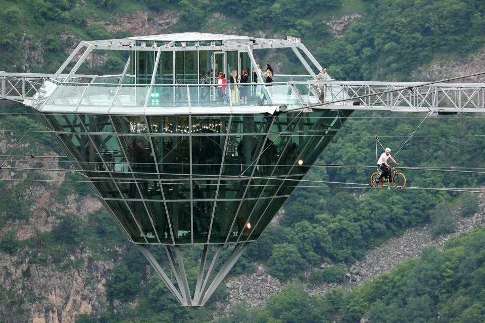 a glass bar suspended in the air in the middle of a glass bridge above Dashbashi Canyon in the country of Georgia
