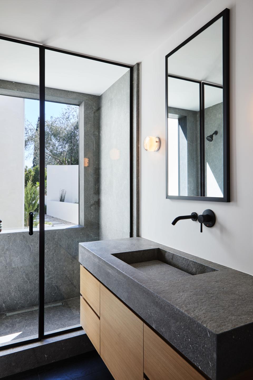 The custom oak cabinetry with hard-brushed Zola gray stone is from Stoneland, and the glass Scotch sconces by Oscar & Sergi Devesa are from Plug Lighting.