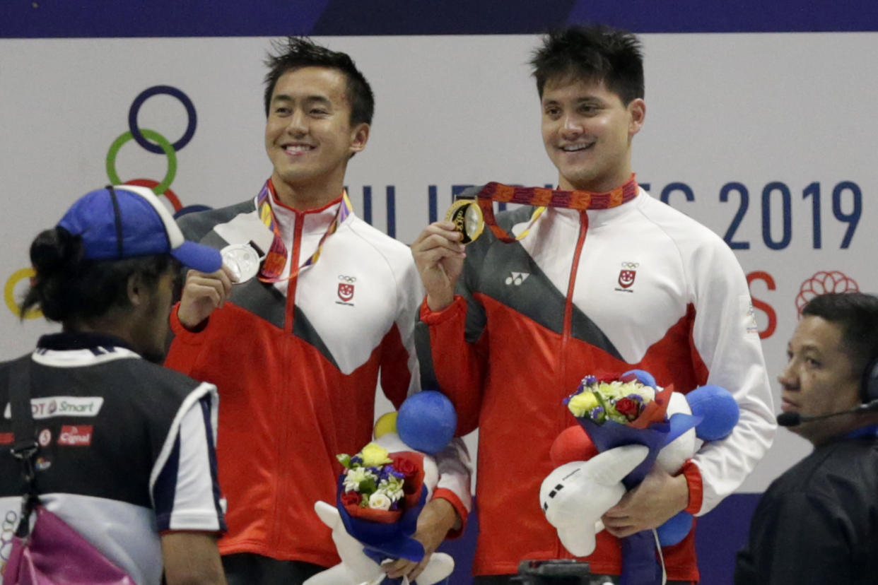 Gold medalist Singapore's Joseph Schooling,right, poses with silver medalist Singapore's Zheng Wen Quah during awarding ceremonies for the men's 100m butterfly final during swimming competition at the 30th Southeast Asian Games in New Clark City, Tarlac province, northern Philippines on Friday, Dec. 6, 2019. (AP Photo/Tatan Syuflana)