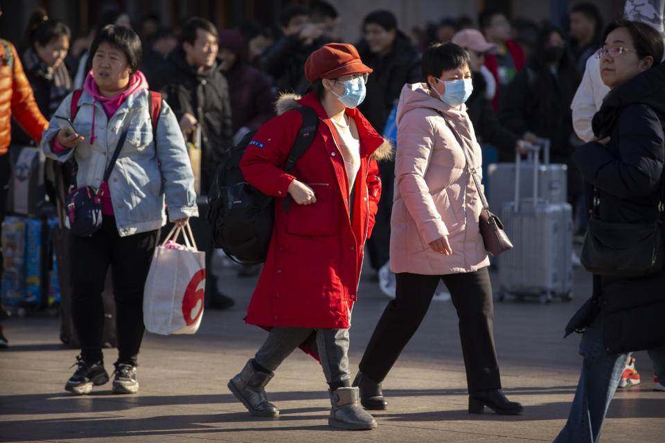 Travelers wear face masks as they walk outside of the Beijing Railway Station in Beijing, Monday, Jan. 20, 2020. China reported Monday a sharp rise in the number of people infected with a new coronavirus, including the first cases in the capital. The outbreak coincides with the country's busiest travel period, as millions board trains and planes for the Lunar New Year holidays. (AP Photo/Mark Schiefelbein)