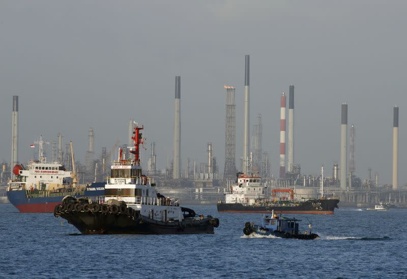 FILE PHOTO: Vessels pass an oil refinery in the waters off the southern coast of Singapore