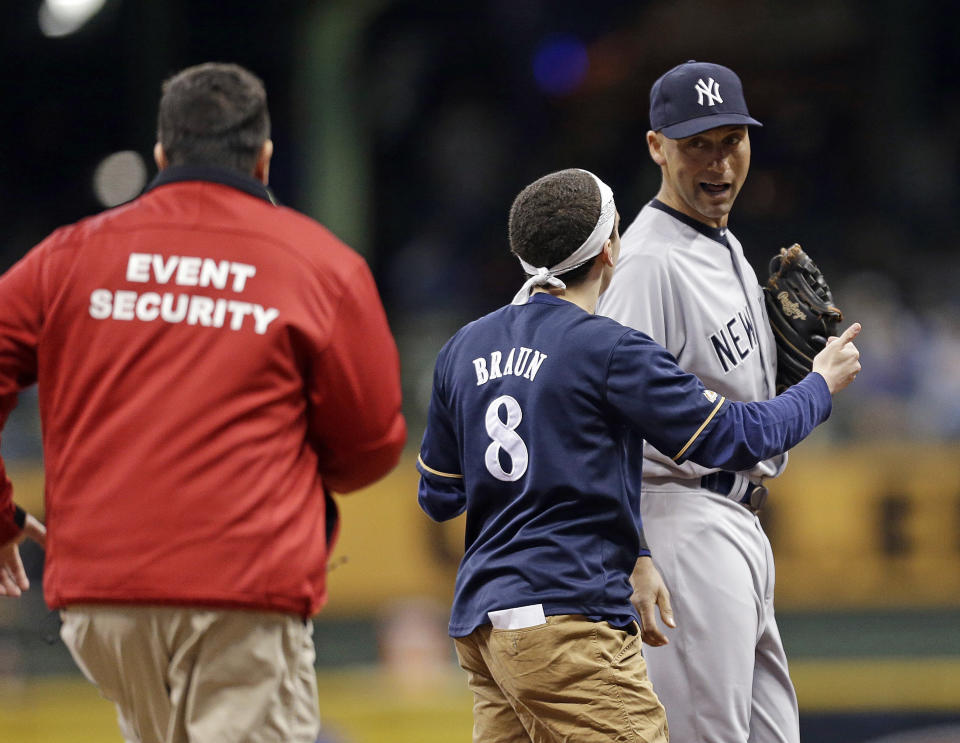 A fan runs out on the field to New York Yankees' Derek Jeter, right, in the sixth inning of a baseball game against the Milwaukee Brewers, Friday, May 9, 2014, in Milwaukee. (AP Photo/Jeffrey Phelps)