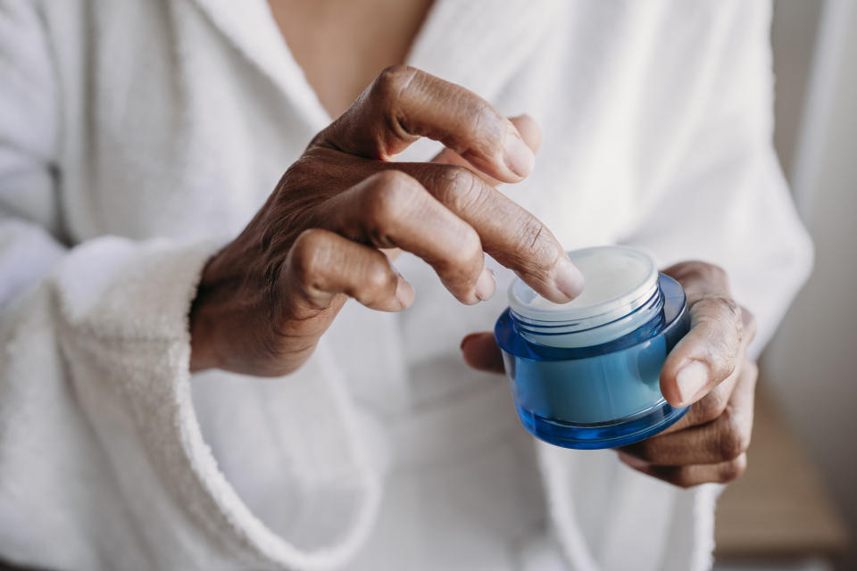 woman using a jar of face cream