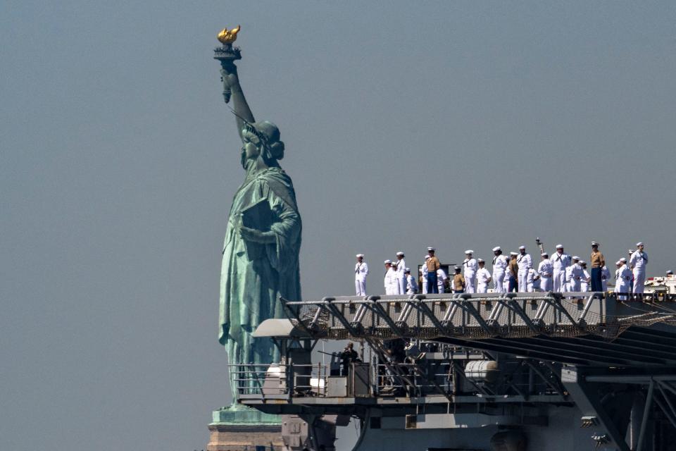 US Sailors and Marines stand on the flight deck of the USS Bataan, a Wasp-class amphibious assault ship, as it passes the Statue of Liberty during Fleet Week in New York Harbor on May 22, 2024.