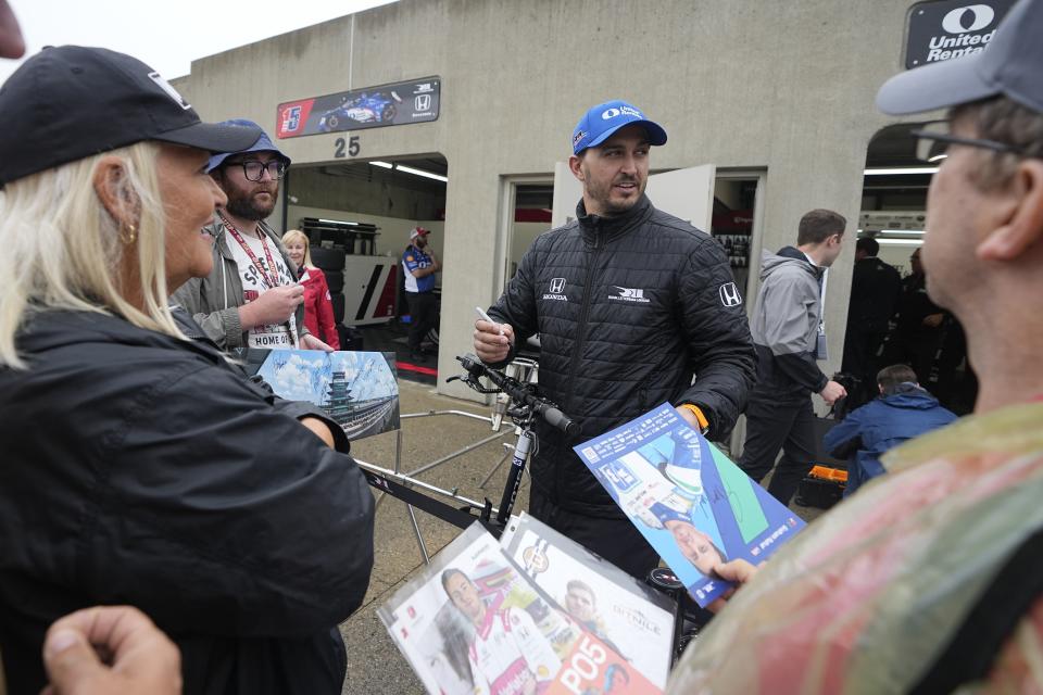 Graham Rahal signs autographs for fans during a rain delay during practice for the Indianapolis 500 auto race at Indianapolis Motor Speedway, Tuesday, May 16, 2023, in Indianapolis. (AP Photo/Darron Cummings)