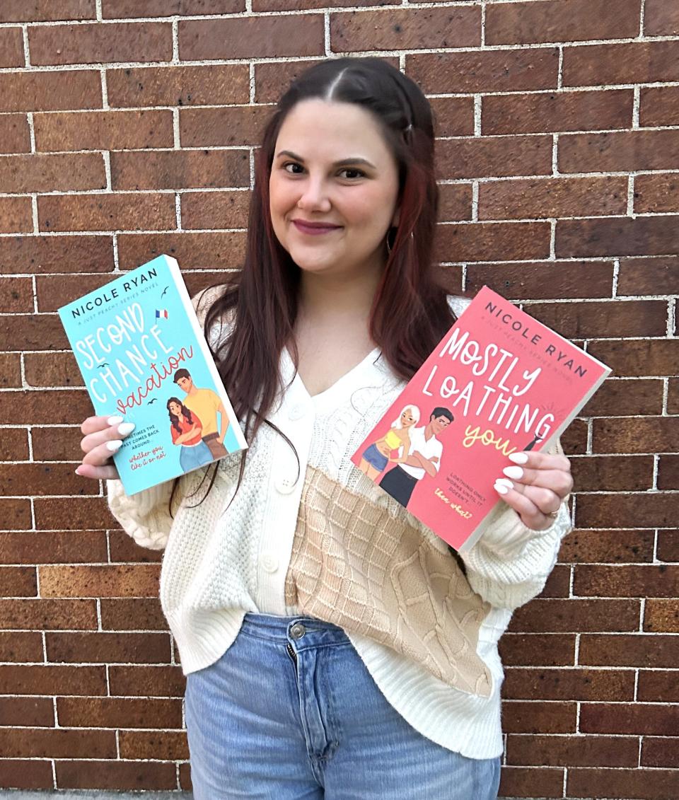 Nicole Ryan holds her first two romance novels and the young author has another slated to release a third book in July 2024.