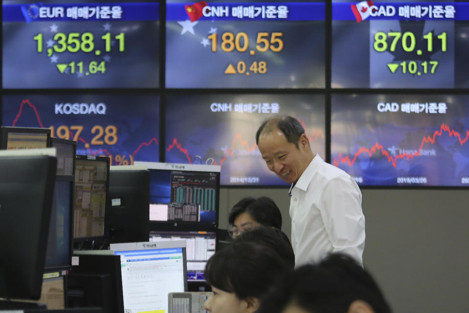 A currency trader smiles at the foreign exchange dealing room of the KEB Hana Bank headquarters in Seoul, South Korea, Wednesday, March 25, 2020. Shares have advanced in Asia after the Dow Jones Industrial Average surged to its best day since 1933 as Congress and the White House neared a deal to inject nearly $2 trillion of aid into an economy ravaged by the coronavirus. (AP Photo/Ahn Young-joon)