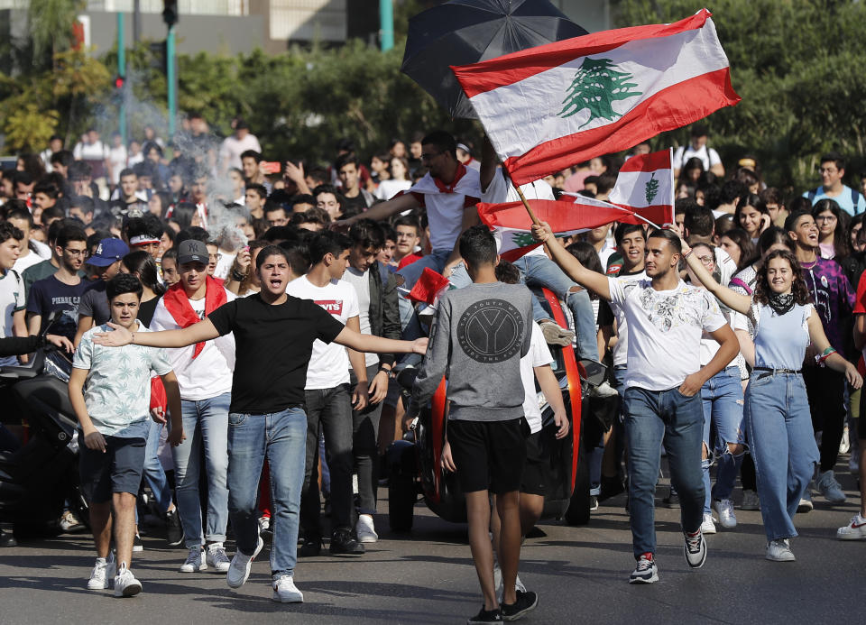 Student protesters wave their national flags and shout slogans, as they protest against the government in front of the education ministry in Beirut, Lebanon, Friday, Nov. 8, 2019. Lebanese protesters are rallying outside state institutions and ministries to keep up the pressure on officials to form a new government to deal with the country's economic crisis. (AP Photo/Hussein Malla)