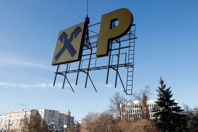 FILE PHOTO: Workers remove a signboard advertising Raiffeisen Bank in Moscow