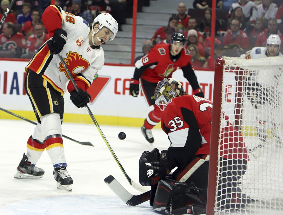Calgary Flames left wing Matthew Tkachuk (19) shoots the puck as Ottawa Senators goaltender Marcus Hogberg (35) makes a save on the play during first-period NHL hockey game action in Ottawa, Ontario, Saturday, Jan. 18, 2020. (Fred Chartrand/The Canadian Press via AP)