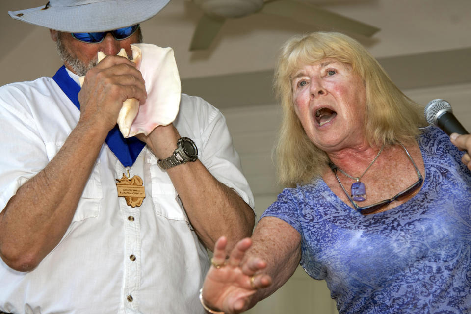 In this photo provided by the Florida Keys News Bureau, Michael Wachter, left, and Georgann Wachter perform during the Conch Shell Blowing Contest, Saturday, March 4, 2023, in Key West, Fla. The couple won the contest's group division by parodying Elvis Presley's "Hound Dog" in an offbeat duet for voice and conch shell. Organized by the Old Island Restoration Foundation, the contest is a Key West tradition that began in 1972. The conch shell is a symbol of the Florida Keys. (Mary Martin/Florida Keys News Bureau via AP)