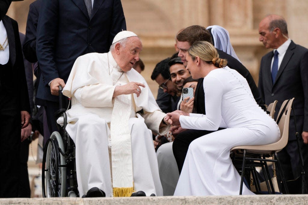 Pope Francis greets a young married couple at the end of his weekly general audience in St. Peter's Square at the Vatican in May 2023. He has formally approved allowing priests to bless same-sex couples.