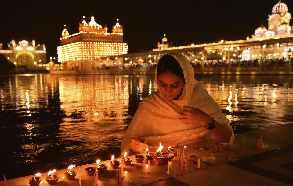 FILE - A Sikh devotee lights candles at the illuminated Golden Temple on the occasion of the birth anniversary of Guru Nanak, the first Sikh Guru and the founder of Sikhism, in Amritsar, India, Tuesday, Nov. 8, 2022. The nones in India come from an array of belief backgrounds, including Hindu, Muslim and Sikh. The surge of Hindu nationalism has shrunk the space for the nones over the last decade, activists say. (AP Photo/Prabhjot Gill)