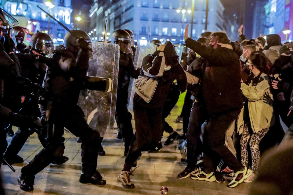 Police officers clash with demonstrators following a protest condemning the arrest of rap singer Pablo Hasel in Madrid, Spain, Wednesday, Feb. 17, 2021. Police fired rubber bullets and baton-charged protesters as clashes erupted for a second night in a row Wednesday at demonstrations over the arrest of Spanish rap artist Pablo Hasel. Many protesters threw objects at police and used rubbish containers and overturned motorbikes to block streets in both Madrid and Barcelona. (AP Photo/Manu Fernandez)