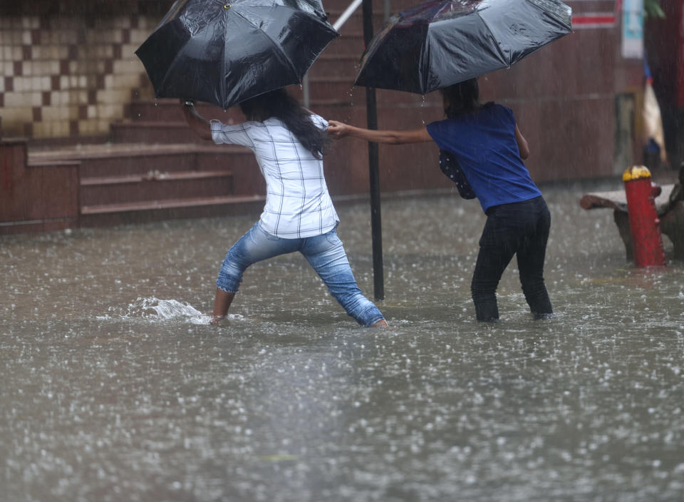 People cross the waterlogged street during heavy rain at Hindmata, Parel, on July 16, 2020 in Mumbai, India. (Photo by Satish Bate/Hindustan Times via Getty Images)