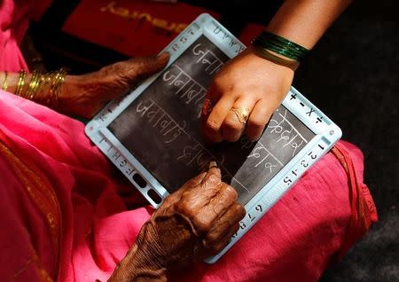 Sheetal Prakash More (R), a 30-year-old teacher, helps Janabai Kedar, 74, as she writes on a slate at Aajibaichi Shaala (Grandmothers' School) in Fangane village, India, February 15, 2017. REUTERS/Danish Siddiqui