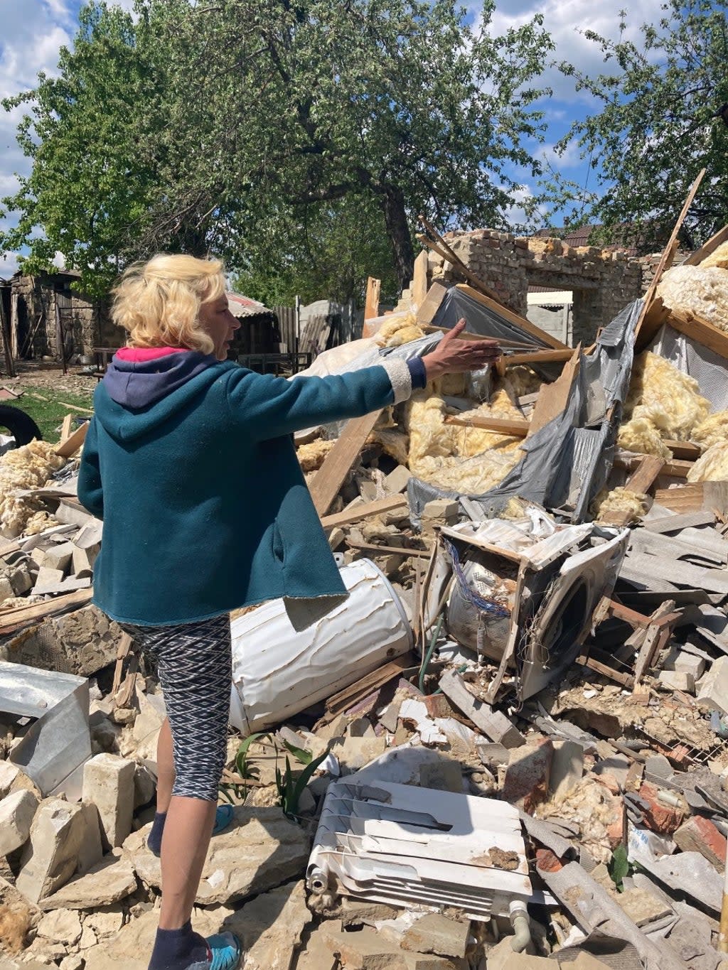 Vasilia Kirilev points to what is left of her home in Vilkhivka near Kharkiv (Demian Shevko)