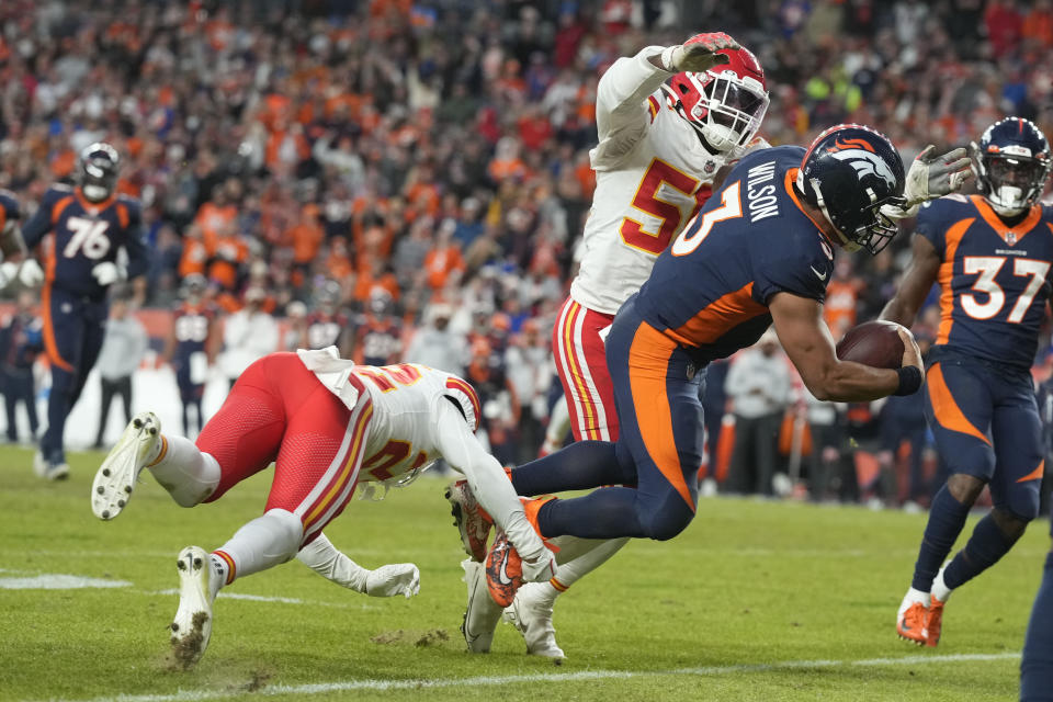 Denver Broncos quarterback Russell Wilson, right, goes down as he is tackled by Kansas City Chiefs defensive end Mike Danna (51) and safety Juan Thornhill (22) during the second half of an NFL football game Sunday, Dec. 11, 2022, in Denver. (AP Photo/David Zalubowski)