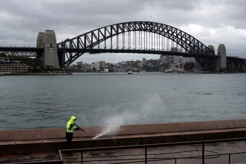 A worker cleans the mostly deserted waterfront area of the Sydney Opera House