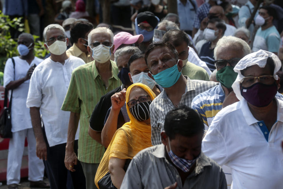 FILE - In this April 26, 2021, file photo, people line up for the coronavirus vaccine in Mumbai, India. As deaths mount and a vaccine rollout falters badly, Prime Minister Narendra Modi has pushed much of the responsibility for fighting the outbreak onto unprepared and poorly equipped state governments. The crisis has badly dented Modi’s carefully cultivated image as an able technocrat. (AP Photo/Rafiq Maqbool, File)