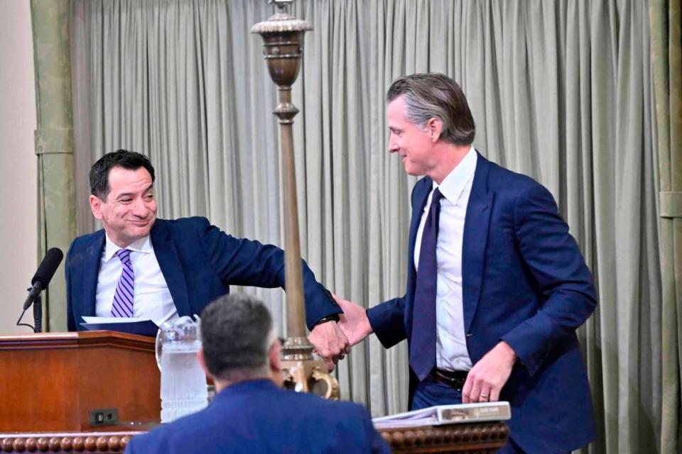 Gov. Gavin Newsom grabs the hand of departing speaker Lakewood Democrat Anthony Rendon while coming up to the podium at the swearing in ceremony for new Assembly Speaker Robert Rivas at the Capitol in Sacramento on Friday, June 30, 2023.