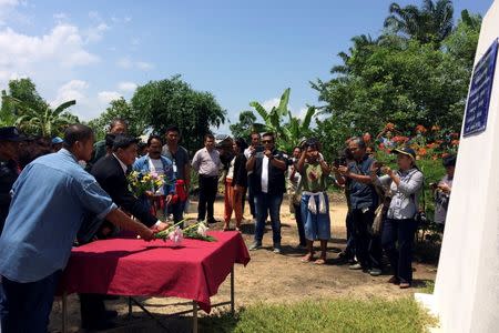 Teeranet Chaisuwan (L), a land rights defender, and deputy permanent secretary of the prime minister's office Jirachai Moontongroy (2nd L) lay flowers in front a memorial for four murdered land rights defenders during a government meeting with villagers in Klong Sai Pattana, south of Thailand, July 1, 2016. REUTERS/Alisa Tang