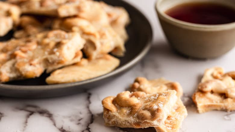 Two pieces of brittle in front of plate and tea cup