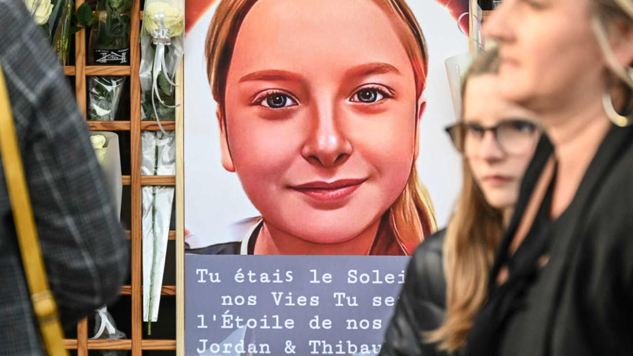 Des habitants se tiennent près d’un portrait de Lola, une fillette de 12 ans qui a été violée et assassinée une semaine auparavant, lors d’une manifestation commémorative pour la fillette, à Fouquereuil, dans le nord de la France, la ville natale du père de la victime, le 21 octobre 2022. - Le corps brutalisé de la victime, identifiée uniquement comme « Lola » par la loi française, a été retrouvé dans une boîte en plastique après avoir été porté disparu dans le nord-est de Paris le 14 octobre. Une femme de 24 ans originaire d’Algérie a rapidement été identifiée comme le principal suspect et placée en détention. La police a déterminé qu’elle avait des antécédents de troubles psychiatriques. (Photo de DENIS CHARLET / AFP)