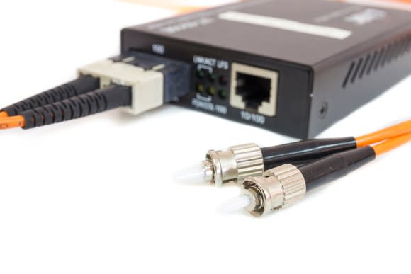 Fiber-optic transceiver with two connected Ethernet cables and two disconnected fiber-optic Lucent connectors.