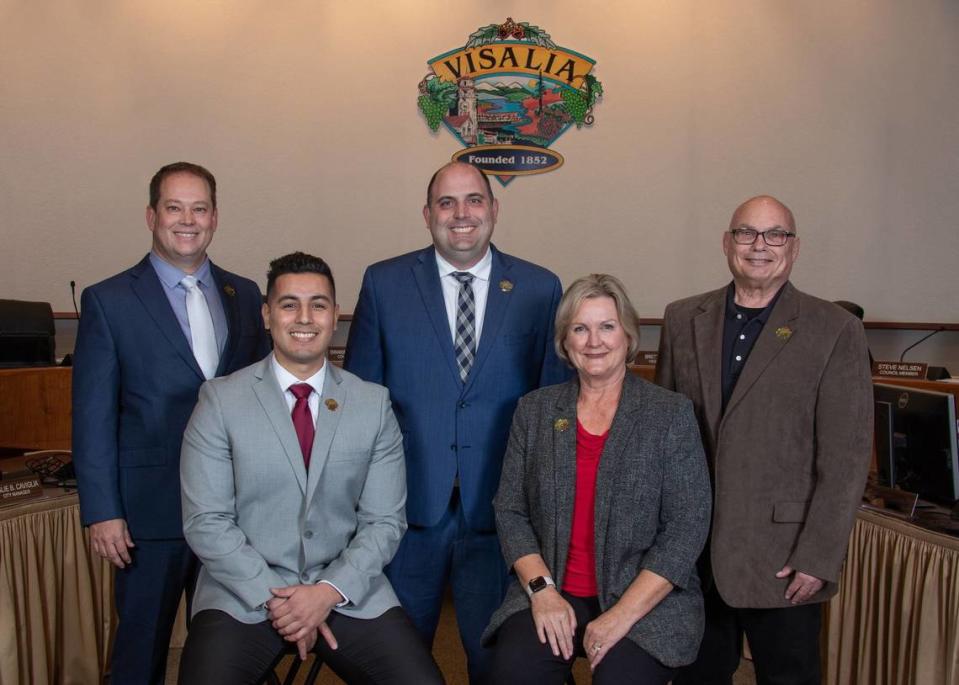 Miembros del Concejo Municipal de Visalia: Vicealcalde Brett Taylor - Distrito 2, Alcalde Brian Poochigian - Distrito 3, Concejal Steve Nelsen - Distrito 5, Concejal Emmanuel Hernández Soto - Distrito 4 y Concejal Liz Wynn - Distrito 1 delante del antiguo logotipo de la ciudad.