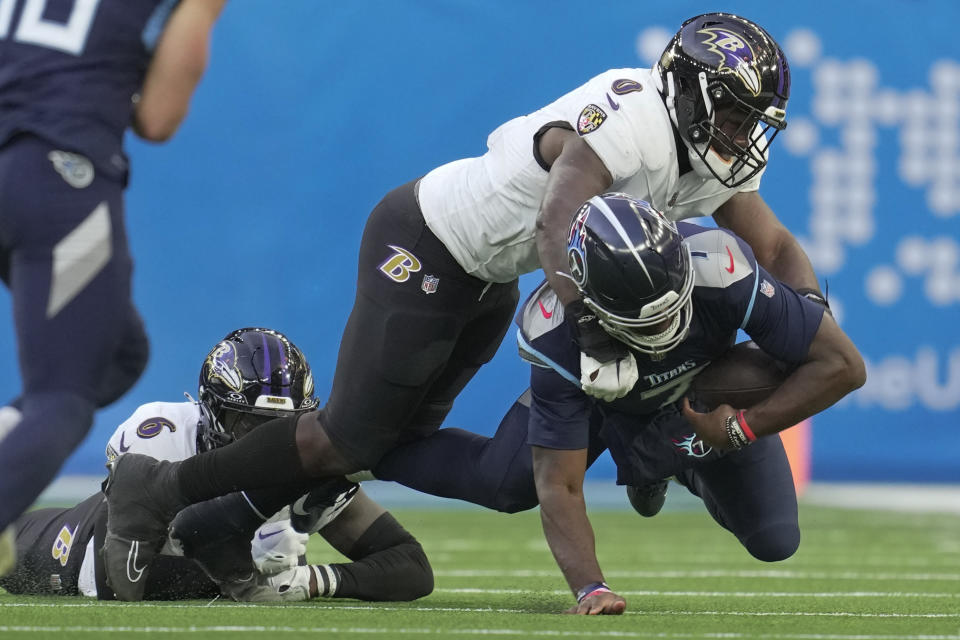 Tennessee Titans quarterback Malik Willis, bottom right, is tackled by Baltimore Ravens linebacker Roquan Smith (0) and linebacker Patrick Queen (6) during the second half of an NFL football game Sunday, Oct. 15, 2023, at the Tottenham Hotspur stadium in London. (AP Photo/Kin Cheung)