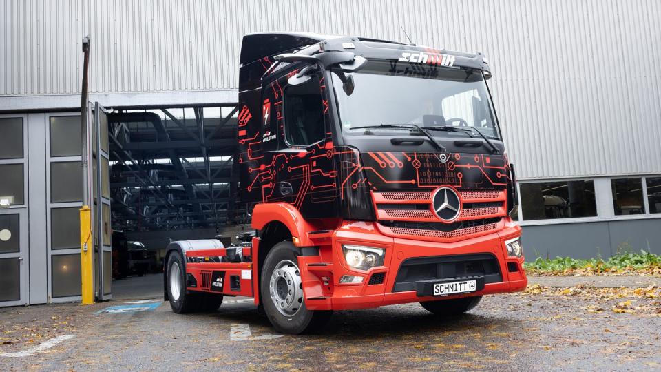 2x4 semi truck with a black ad red cab sits outside a garage in germany