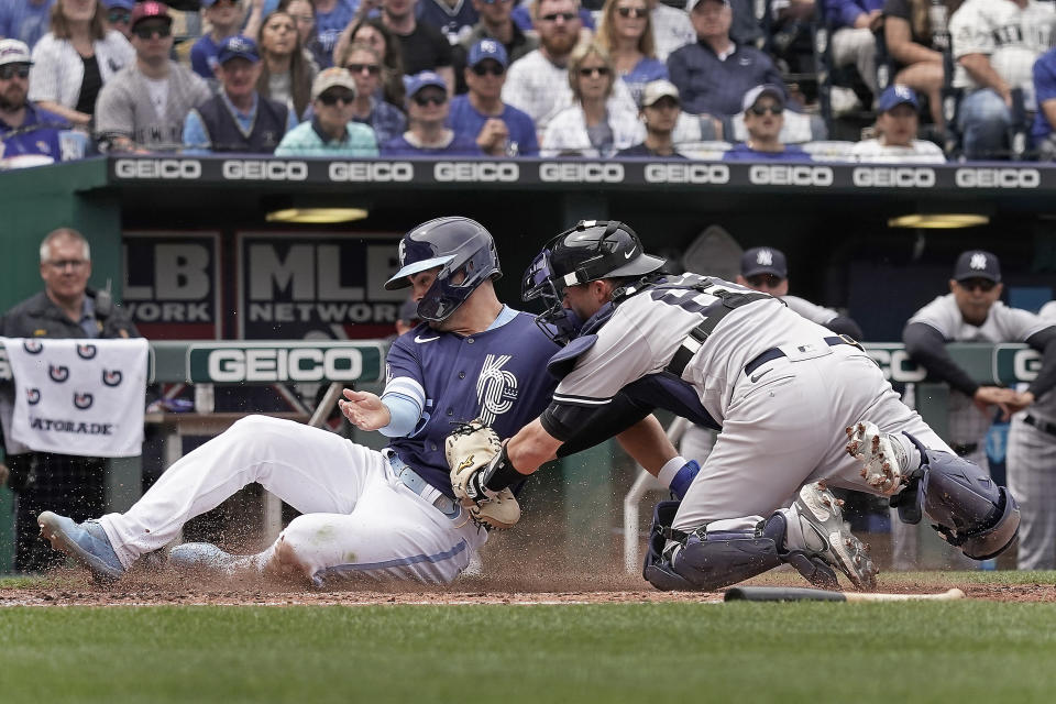 Kansas City Royals' Whit Merrifield, left, is tagged out by New York Yankees catcher Kyle Higashioka as he tried to score on a fielder's choice hit by Salvador Perez during the third inning of a baseball game Sunday, May 1, 2022, in Kansas City, Mo. (AP Photo/Charlie Riedel)