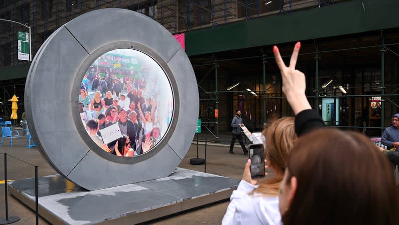 People interact with a massive circular livestream video "portal" connecting Manhattan's Flatiron District with a portal in Dublin on May 10, 2024, in New York City.