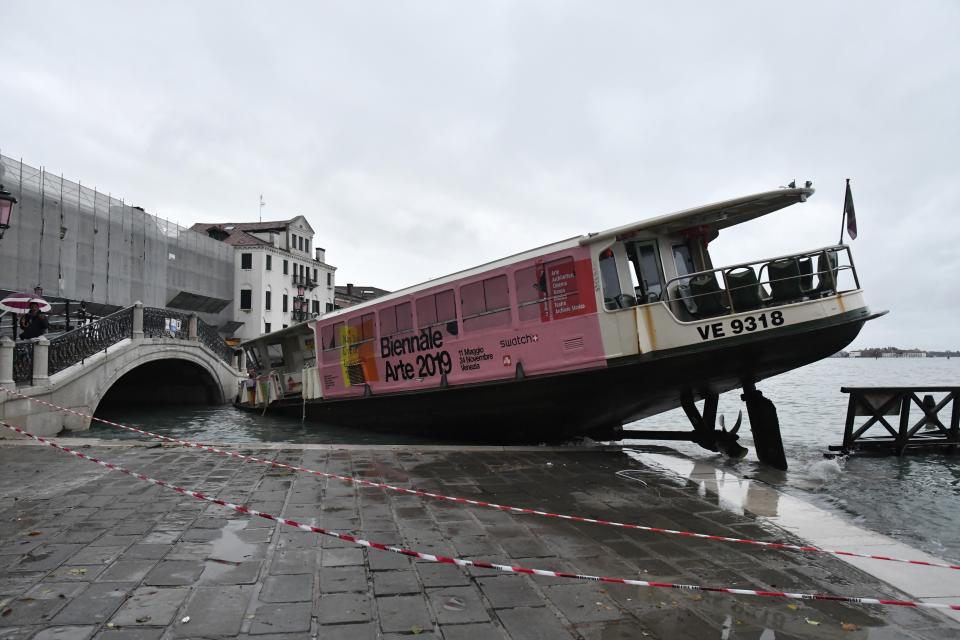 A stranded ferry boat lies on its side, in Venice, Wednesday, Nov. 13, 2019. The mayor of Venice is blaming climate change for flooding in the historic canal city that has reached the second-highest levels ever recorded, as another exceptional water level was recorded Wednesday. The high-water mark hit 187 centimeters (74 inches) late Tuesday, meaning more than 85% of the city was flooded. (AP Photo/Luigi Costantini)
