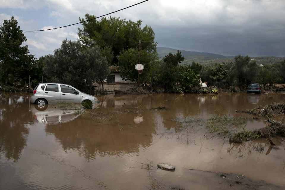 Damaged cars abandoned at a flooded area outside a house following a storm near the village of Politika, on Evia island, northeast of Athens, on Sunday, Aug. 9, 2020. Five people, including en elderly couple and an 8-month-old baby have been found dead, two more are missing and dozens have been trapped in their homes and cars as a storm hits the island of Evia in central Greece, authorities said Sunday. (AP Photo/Yorgos Karahalis)