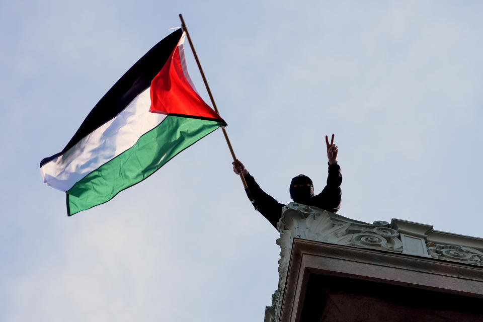 FILE - A student protester waves a Palestinian flag above Hamilton Hall on the campus of Columbia University, Tuesday, April 30, 2024, in New York. (Pool Photo/Mary Altaffer, File)