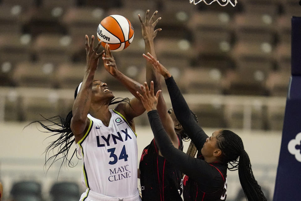 Minnesota Lynx center Sylvia Fowles (34) goes up for a rebound with Indiana Fever center Queen Egbo, center, and guard Victoria Vivians in the first half of a WNBA basketball game in Indianapolis, Friday, July 15, 2022. (AP Photo/Michael Conroy)