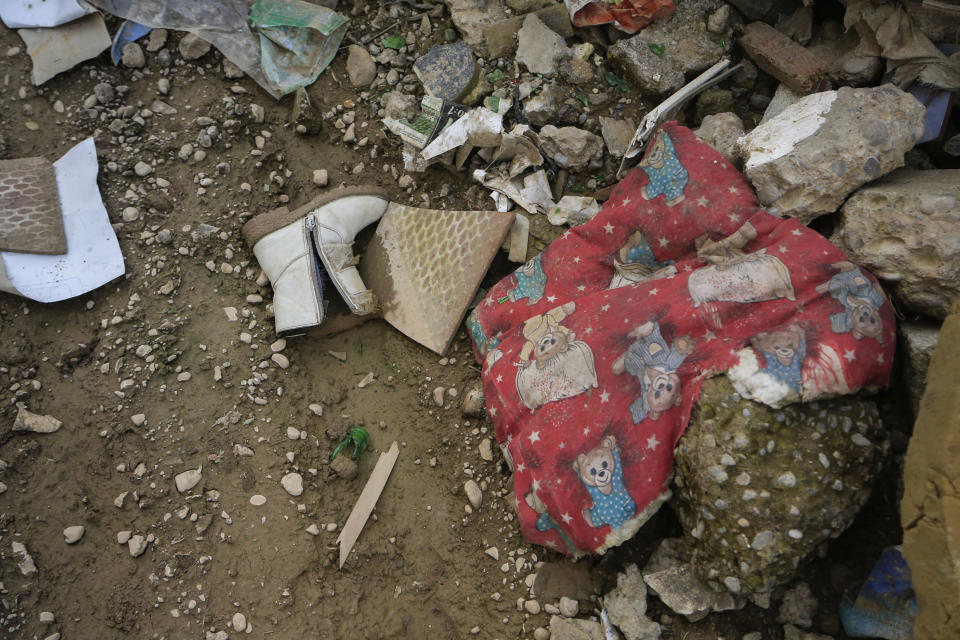 In this Jan. 18, 2019 photo, a child’s boot and blanket lie in the ruins of a Christian house destroyed during fighting with the Islamic State group, in Bartella, Iraq. Two years after Bartella was liberated from IS, fewer than a third of its 3,800 Christian families have come back. Most remain afraid, amid reports of intimidation and harassment by Shabak, who dominate the Shiite militias now controlling the town. (AP Photo/Fay Abuelgasim)